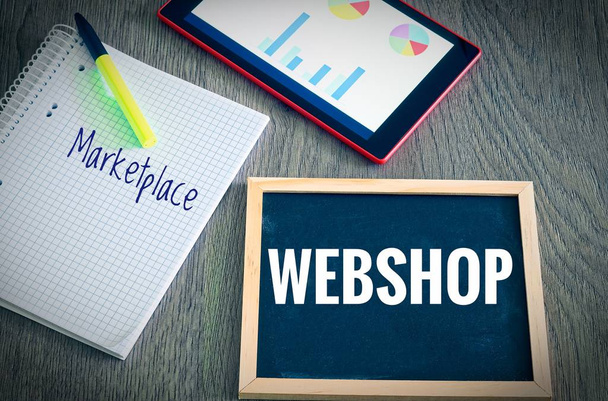 Platte mit der Beschriftung Webshop und Marktplatz mit Tablette Grafiken und Statistiken und Block, um die Umsatzsteigerung eines Online-Shops zu veranschaulichen - Foto, Bild