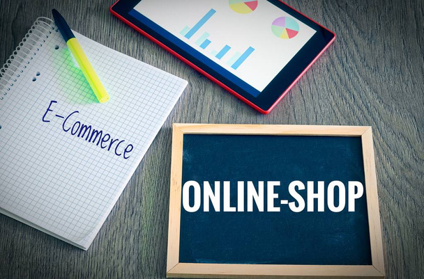 Platte mit der Beschriftung Webshop und E-Commerce mit einem Tablet Grafiken und Statistiken und Block, um die Umsatzsteigerung eines Online-Shops zu veranschaulichen - Foto, Bild