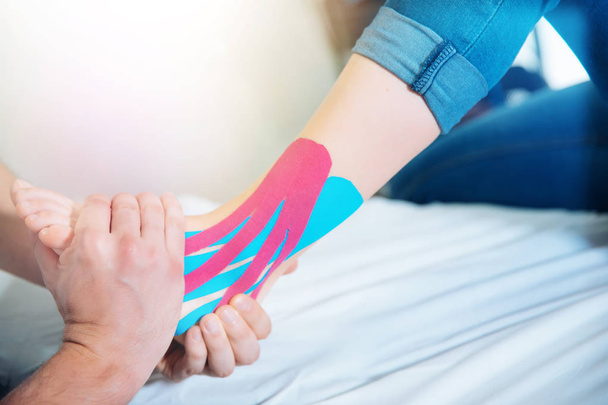 Fysiotherapeut kinesio tape plaatsen patiënt voet - Foto, afbeelding