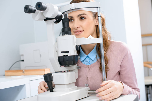 young woman at slit lamp in oculist consulting room - 写真・画像