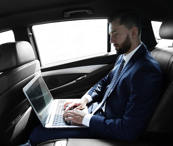 businessman using a laptop in the backseat of a car - Фото, зображення