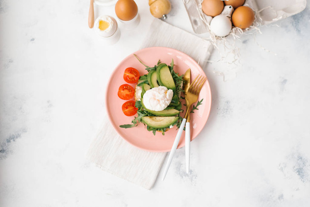 Composición alimenticia de ensalada de verduras sobre plato rosado con cuchillo, tenedor, cucharas y huevos sobre fondo
 - Foto, imagen