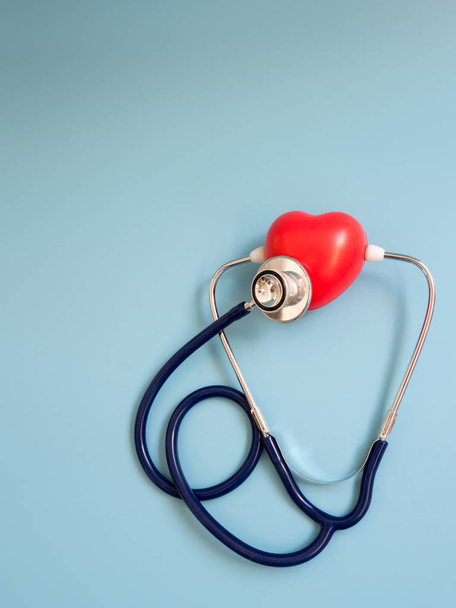 rotes Herz mit tiefblauem Stethoskop auf blauem Hintergrund, um ihr eigenes Herz zu hören. Konzept der Liebe und fürsorglichen Patienten durch das Herz. Kopierraum für Text und Inhalt - Foto, Bild