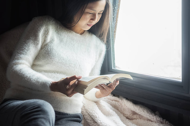 Egy könyvet olvas. Gyönyörű női ül az ágyon és olvasás  - Fotó, kép