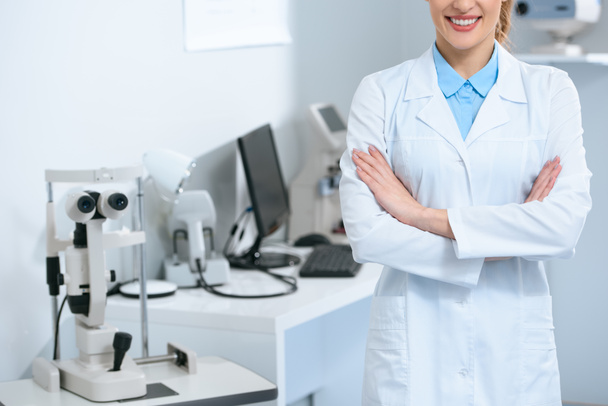 vista ritagliata dell'oftalmologo femminile in piedi con braccia incrociate in clinica ottica
 - Foto, immagini