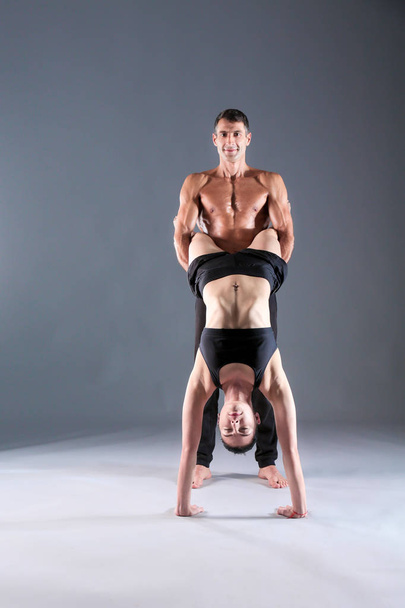 Young couple practicing acro yoga on mat in studio together. Acroyoga. Couple yoga. Partner yoga. - Foto, Imagem