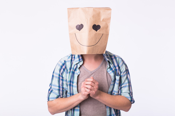 Любов, емоції та концепція стосунків - людина з картонною коробкою на голові з емальованим обличчям
. - Фото, зображення