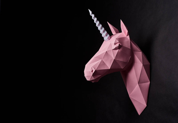 Sideview of pink shadowed unicorns head hanging on wall. - 写真・画像