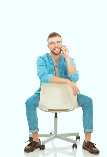 Young man sitting on chair and using mobile phone. Startupper. Young entrepreneur. - Fotó, kép