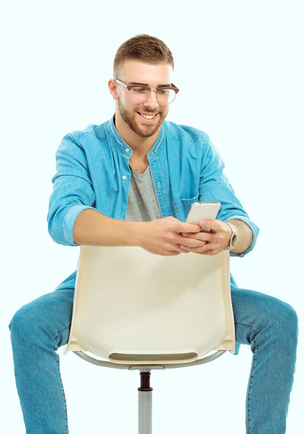 Young man sitting on chair and using mobile phone. Startupper. Young entrepreneur. - Fotó, kép