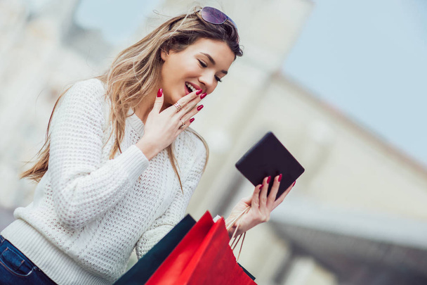 Όμορφη γυναίκα με Τσάντες για ψώνια στην πόλη χρησιμοποιώντας ψηφιακό tablet - Φωτογραφία, εικόνα