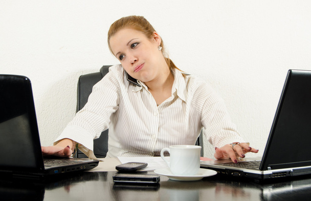 τόνισε multitasking γυναίκα επιχειρήσεων στο γραφείο της, χρησιμοποιώντας την τελευταία λέξη της τεχνολογίας. - Φωτογραφία, εικόνα
