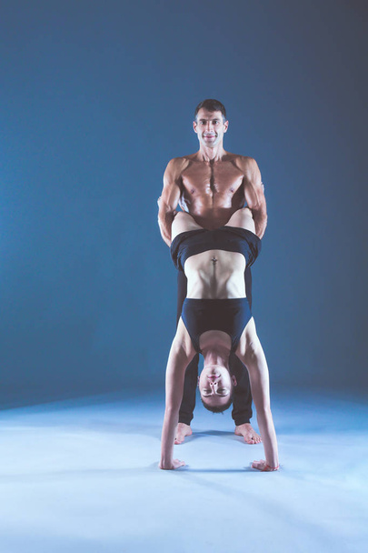 Young couple practicing acro yoga on mat in studio together. Acroyoga. Couple yoga. Partner yoga. - Foto, afbeelding