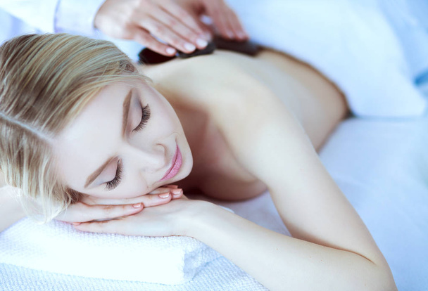 Jeune femme allongée sur une table de massage, relaxante les yeux fermés. Femme. Salon de spa - Photo, image