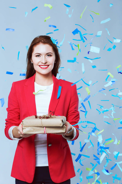 Beautiful happy woman with gift box at celebration party with confetti . Birthday or New Year eve celebrating concept - Photo, image