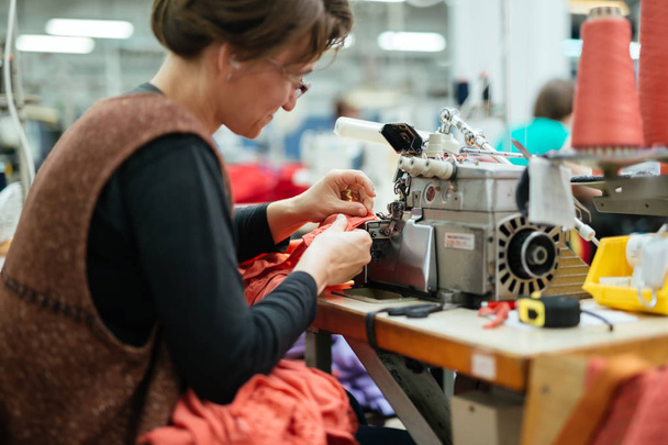 Woman working on a sewing machine in textile industry - Фото, изображение