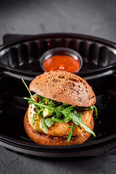 Vegetarische hamburger met rode saus in zwarte doos - Foto, afbeelding