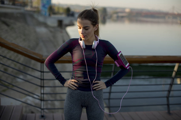Aantrekkelijke vrouwelijke atleet nemen pauze na het joggen buiten - Foto, afbeelding
