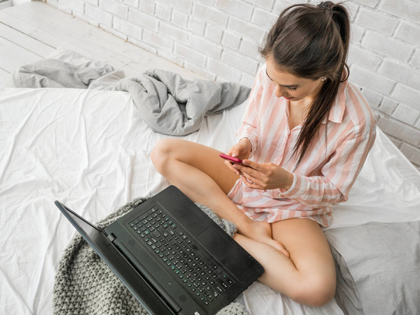 Vista superior de la mujer que trabaja con el ordenador portátil en la cama
 - Foto, imagen