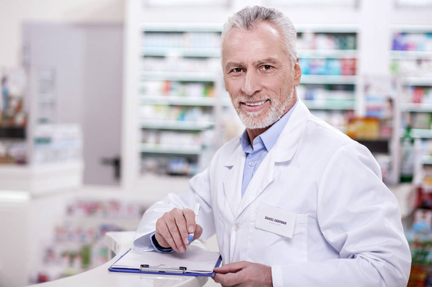 Optimistic male pharmacist filling up documentation - Zdjęcie, obraz