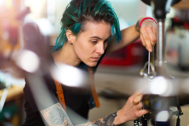 Zeker jonge vrouw werkt in een fietswinkel voor reparatie - Foto, afbeelding