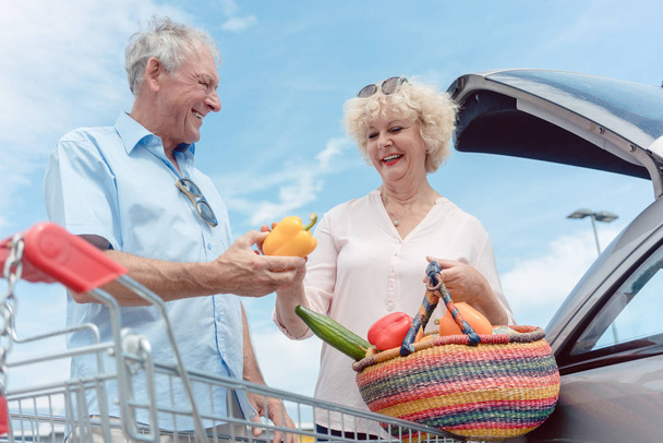 大型スーパー マーケットからの新鮮な野菜を購入するため幸せな陽気な年配のカップル - 写真・画像