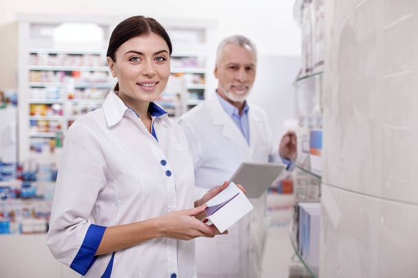 Happy female pharmacist overseeing drugs - Photo, Image