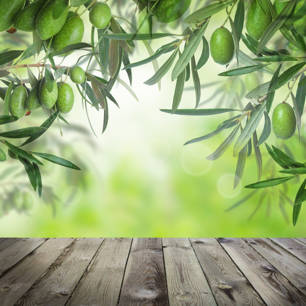 緑の葉とオリーブ、夏ボケの光と木のテーブル - 写真・画像