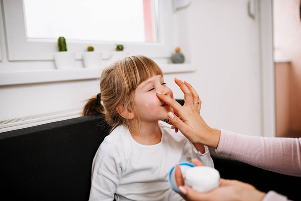 mother putting face cream on little daughter - Valokuva, kuva