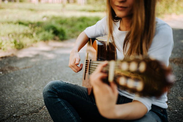 Young woman playing acoustic guitar in city park - Foto, imagen