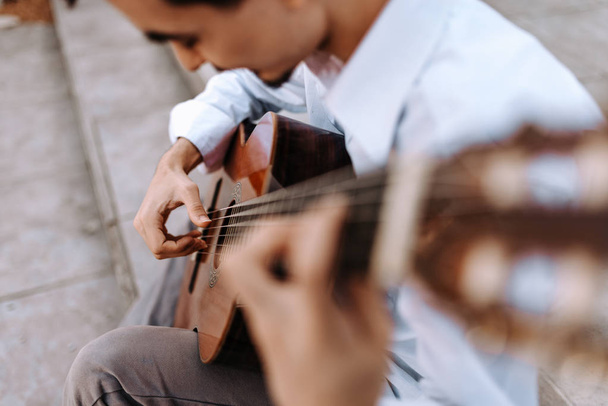 Young man playing acoustic guitar in city street - Fotó, kép