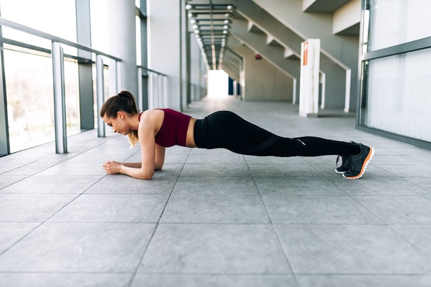 Side portrait of healthy young woman doing plank exercise - Fotó, kép
