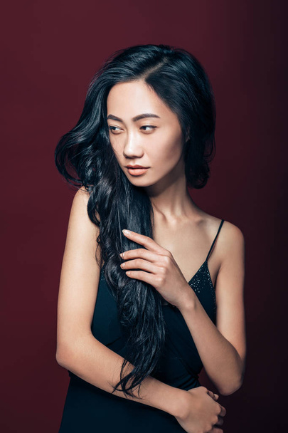 Beautiful asian woman in black dress posing in studio on brown background. Pretty fashion model portrait - Foto, Bild