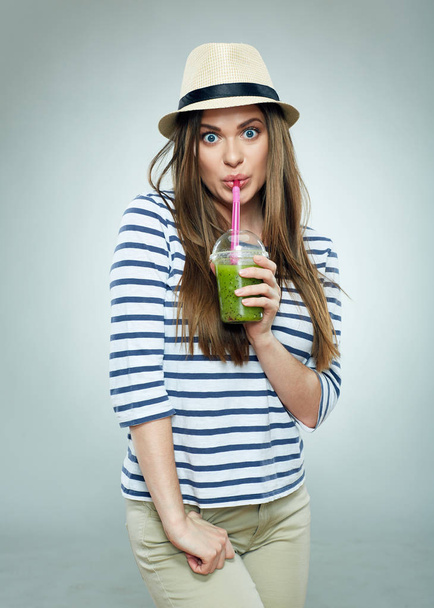 woman dressed in casual clothes and hat drinking detox cocktail from straw - Foto, afbeelding