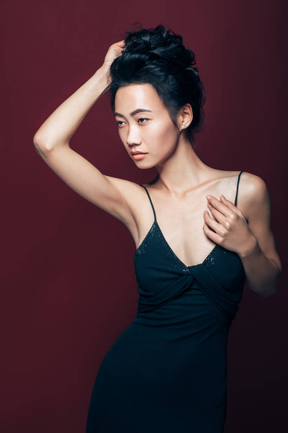 Beautiful asian woman in black dress posing in studio on brown background. Pretty fashion model portrait - Fotoğraf, Görsel