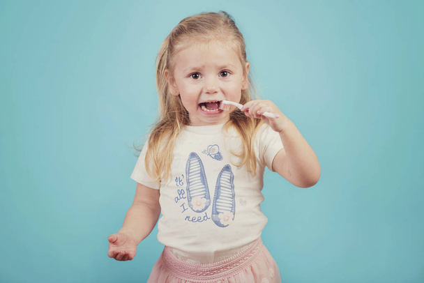 menina com escova de dentes no fundo azul
 - Foto, Imagem