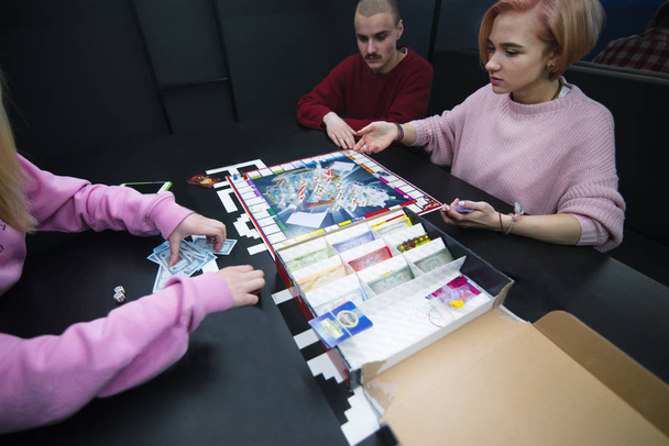 Mladí lidé sedí u stolu a hrát monopol. Deskové hry s přáteli. - Fotografie, Obrázek