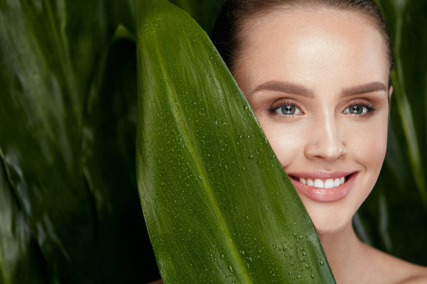 Natural Cosmetics. Beautiful Woman Face With Green Plant - Fotoğraf, Görsel