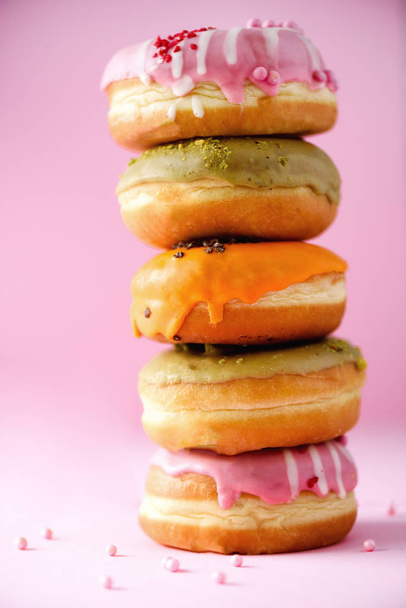 Sweet and colourful doughnuts on pink background. Fresh baked donuts. Copy space. - Foto, Imagen