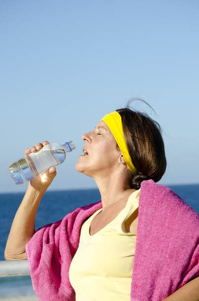 Exercising mature woman drinking water beach - Foto, Imagen