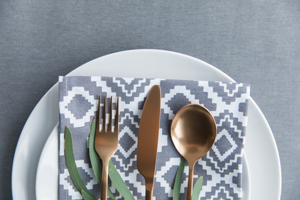 flat lay with rustic table setting with vintage tarnished silverware, napkin, green plant and plate - Photo, Image