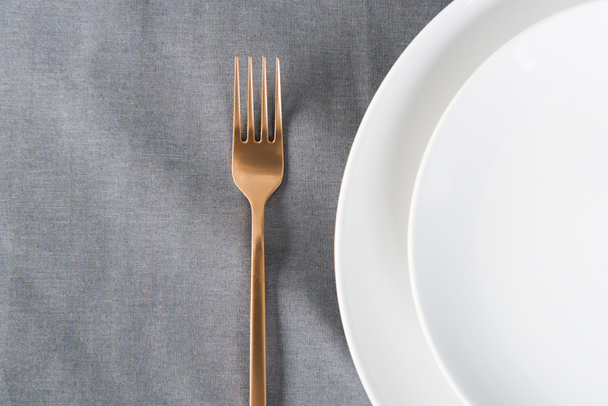 top view of arranged tarnished old fashioned fork and empty plates on tabletop - Foto, Imagem
