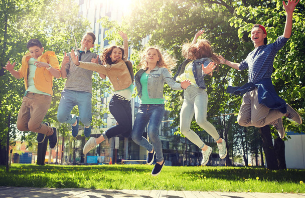 happy teenage students or friends jumping outdoors - Foto, afbeelding