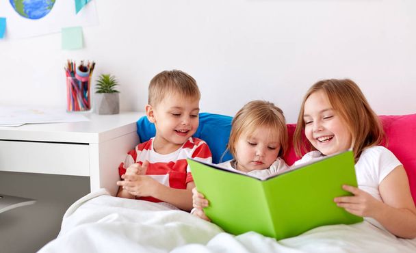 little kids reading book in bed at home - Foto, Imagen