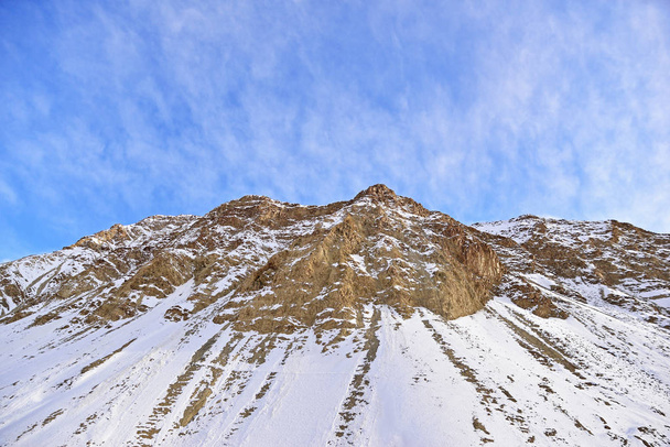 Closeup of winter snow covered mountain peaks with blue sky in L - Foto, afbeelding