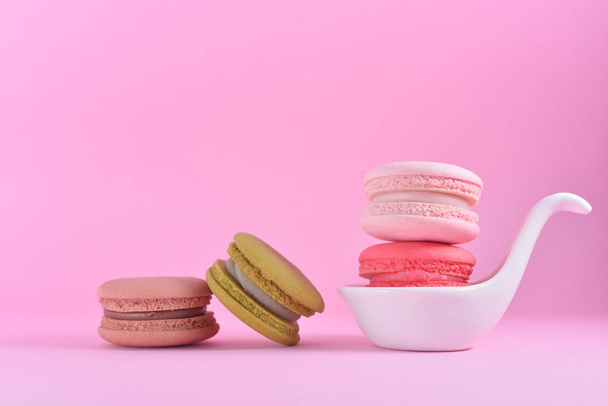Macarons coloridos franceses em copo de cerâmica branca em rosa pastel ba
 - Foto, Imagem