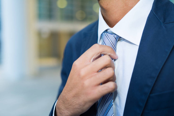 Szczegóły biznesmen, dostosowując jego krawat - Zdjęcie, obraz