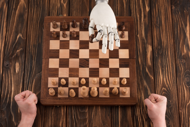 tiro cortado de robô jogando xadrez com humano na superfície de madeira
 - Foto, Imagem