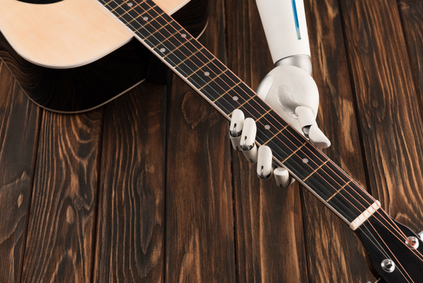 木製の表面上のアコースティック ギターを演奏するロボットのショットをトリミング - 写真・画像