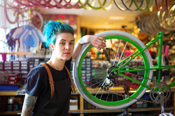 Confident young woman working in a bicycle repair shop - Photo, Image